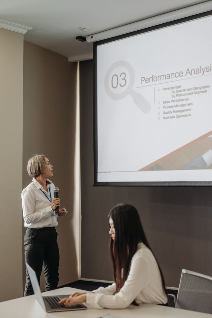 The Art of Drawing Readers In: Your attractive post title goes here Professional business presentation with women using microphone and projector.